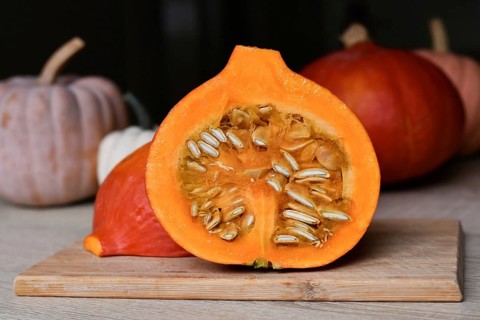 Halved Hokkaido pumpkin showing seed on cutting board in kitchen