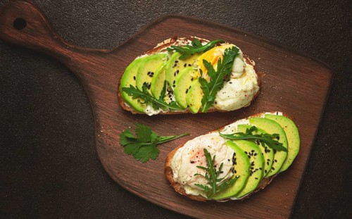 Sandwich with cream cheese, sliced avocado and boiled egg, arugula, on grainy bread, homemade,
