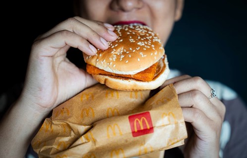 A woman eats a McDonald's burger on October 26, 2024 in Guwahati, India. McDonald's recent food