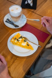 A slice of pumpkin pie on a plate and a cup of latte macchiato on a wooden table, autumn creations