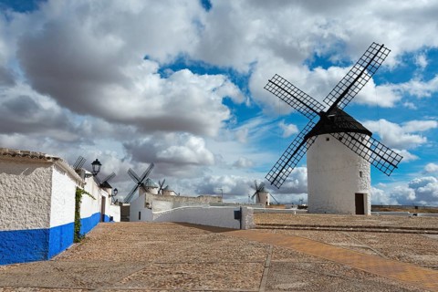 White windmills with blue stripes on old cobbled streets under a cloudy sky, Molino Sardinero,
