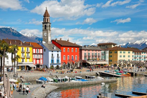 Colourful house facades on the lakeside promenade of Ascona on Lake Maggiore, with snow-capped