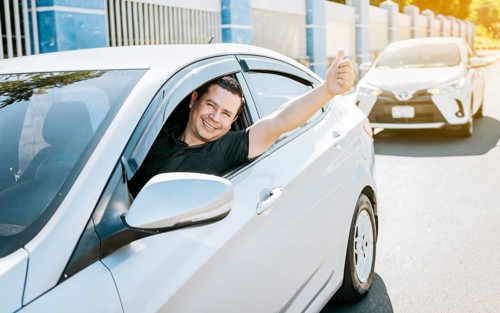 Smiling driver giving a thumbs up on the road. Satisfied driver man showing thumb up, safe driving