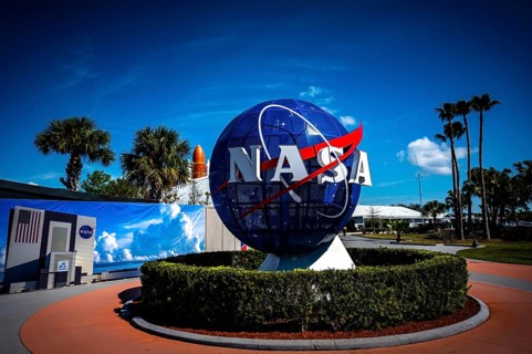 NASA logo with globe in front of blue sky and palm trees at the Kennedy Space Center, Cape