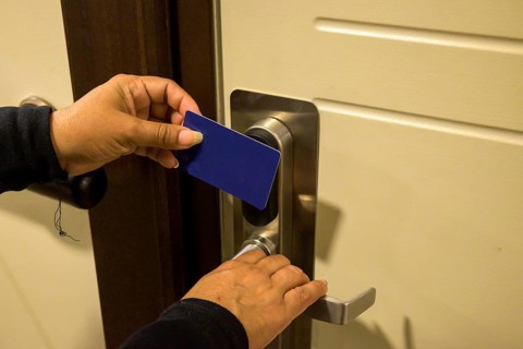 Hands holding a keycard near a door lock for entry, key electronic lock, hotel room, holidays in