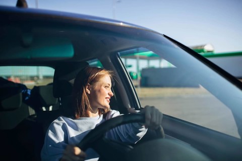 Young beautiful woman driver driving a car, happy trip, spring travel