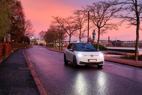 White Volkswagen ID3 electric car driving on seaside street at beautiful morning dusk, copy space.