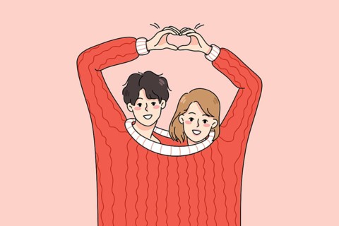 Cute happy couple lovers wearing one sweater make heart hand gesture. Smiling man and woman hug
