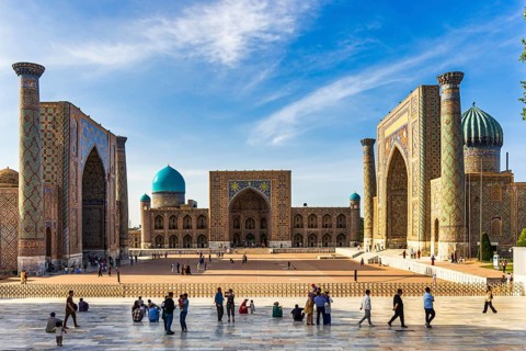 Registan square with three madrasahs and tourists on the observation platform