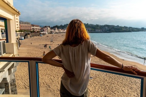 A young woman looking at the beautiful Grande Plage in Saint Jean de Luz at sunset, vacation in the