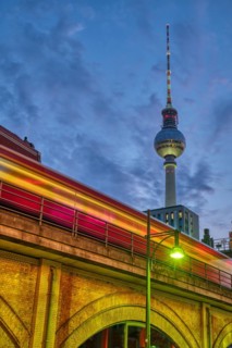 The famous TV tower in Berlin at dusk with a motion blurred local train