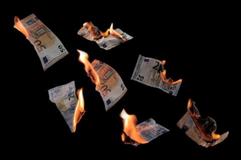 Burning money, twenty and fifty euro banknotes with flames flying isolated against a black
