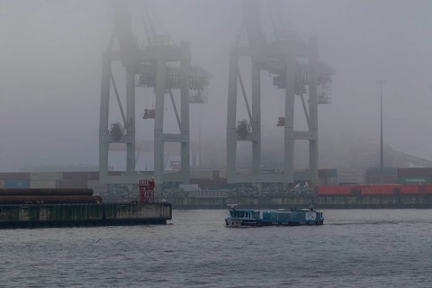 Weather, heavy fog in winter, barge on the Elbe and container gantry cranes in dense fog at the