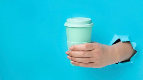 Front view hand holding reusable cup with copy space