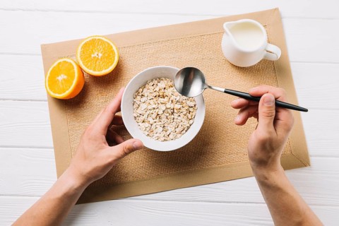 Person having oatmeal halved orange milk jute placemat white surface. High resolution photo