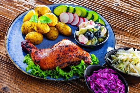 Baked chicken leg with potatoes and vegetable salads