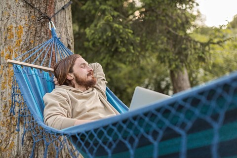 Man hammock enjoying nature with laptop