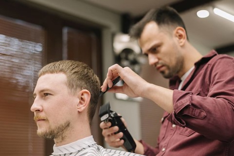 Low angle hairstylist giving haircut