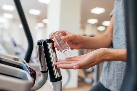 Side view woman using hand sanitizer gym during pandemic