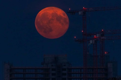 The full moon passes over a construction site in Offenbach am Main. A super moon will shine from