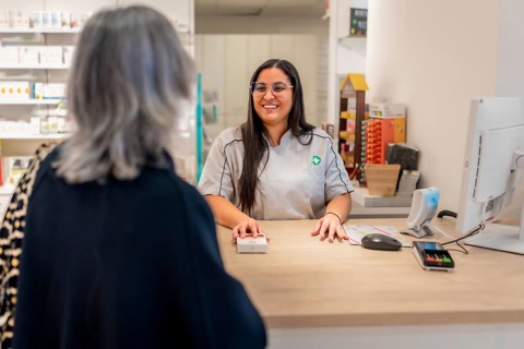 Friendly pharmacist talking to a mature female customer in the counter
