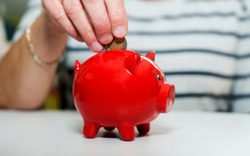 Female hand putting euro in money pig Female hand putting euro in money pig, saving money for later