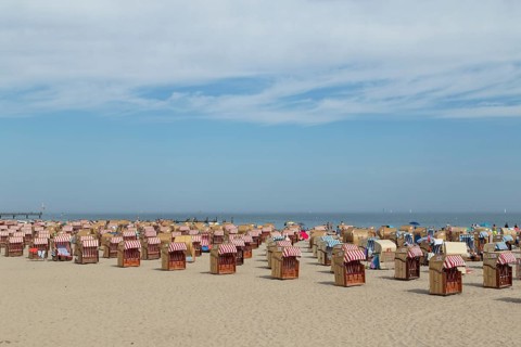 Symbolic picture weather, summer, bathers and beach chairs in front of a blue sky on the sandy