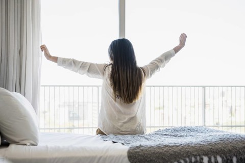 Rear view woman sitting bed stretching her arms. Resolution and high quality beautiful photo