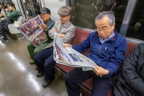 Tokyo Japan. Senior passengers on the metro, reading newspapers