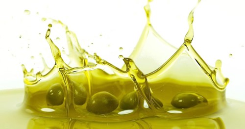 Olives Falling into Olive Oil against White Background