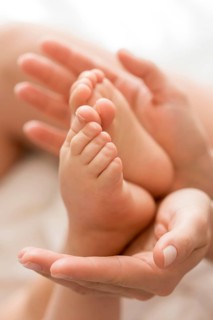 Close up mom holding baby s feet hands