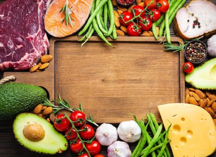 Wooden cutting board and ketogenic low carbs ingredients for healthy weight loss diet, top view,