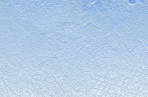 Close-up view of a cracked ice surface with a blue and white color palette, evoking a sense of cold