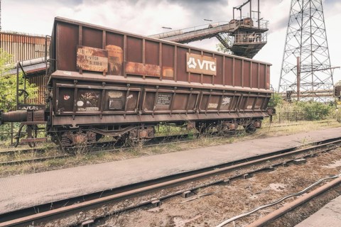 Rusty freight wagon on abandoned rails in an industrial plant, cloudy sky, steelworks HF4, Lost