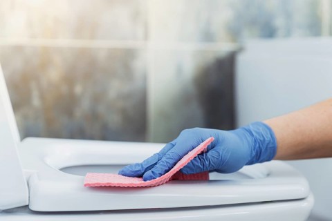 Cropped image view with close up on woman hands gloved in rubber protective gloves. Housewife