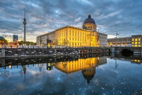 The rebuilt Berlin City Palace with the television tower and some dark storm clouds at dawn