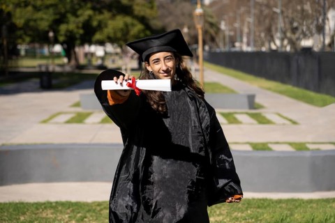 Woman recent graduated, dressed in cap and gown, showing off his degree celebrating