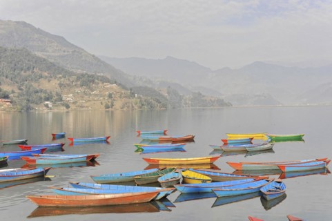 Colourful boats on the water are reflected in the mountain landscape, Pokhara Valley, Pokhara,