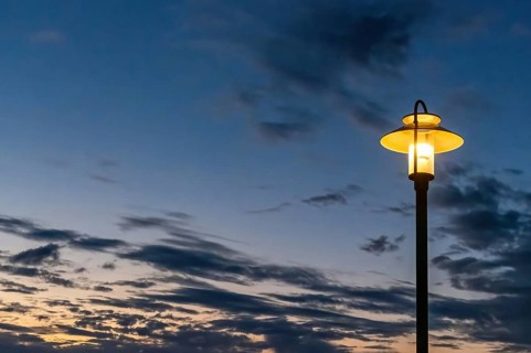 Illuminated street lamp in front of a rainy autumn sky