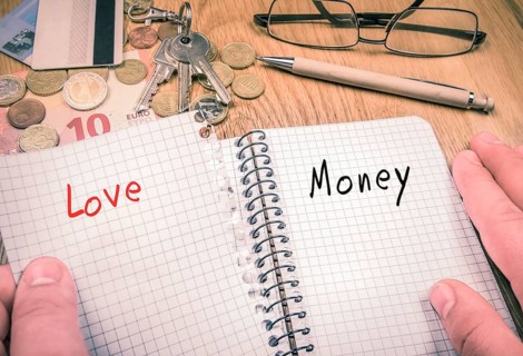 Man's hands ripping a sheet with the word love, remaining the page with the word money in the