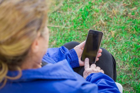 Close up of a woman's wrinkled finger, touching on a cell phone