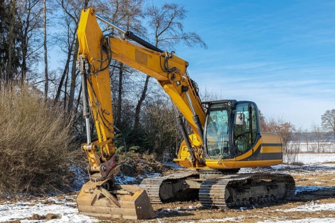Large excavator parked in a meadow in winter