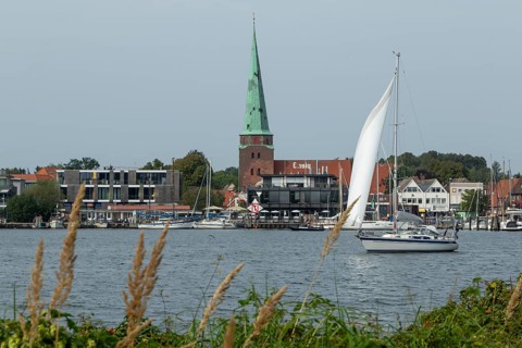 View from Priwall onto the river Trave with sailing boat and St Lorenz church, seaside resort