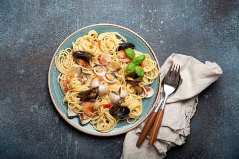 Italian seafood pasta spaghetti with mussels, shrimps, clams in tomato sauce with green basil on