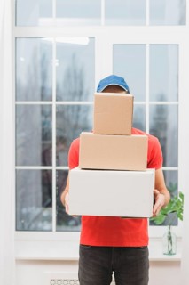 Faceless courier with stack parcels