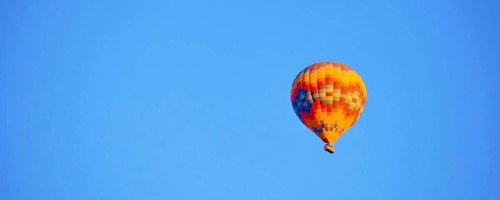 Flying hot air balloon against bright blue sky