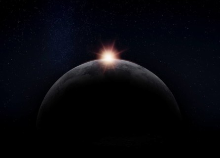 View of the dark hidden side of the Moon with the Sun behind it. Negative space for copy text.