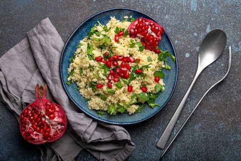 Bright colourful couscous or bulgur salad with pomegranate seeds Tabbouleh in rustic blue ceramic