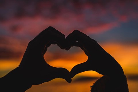 Couple making heart shape from hands sea shore