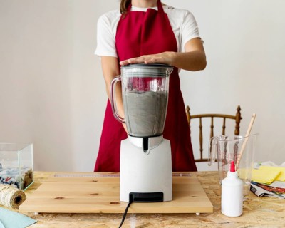 Midsection view woman grinding paper pulp mixer